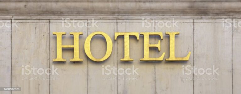 Hotel sign on stone wall building facade, golden letters text front view